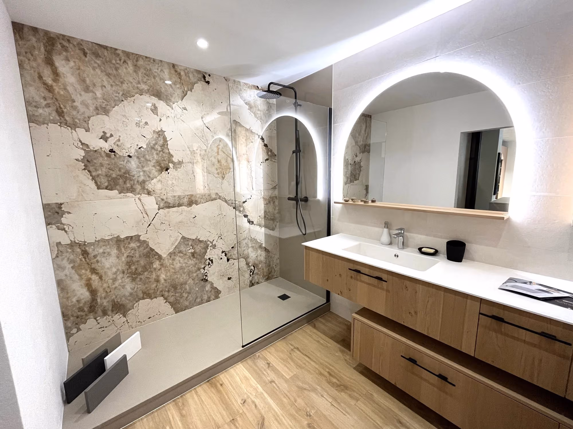 Meuble vasque en bois, miroir en arche éclairé et douche vitrée avec revêtement à motifs de pierre